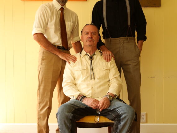 A portrait of three men in a yellow room
