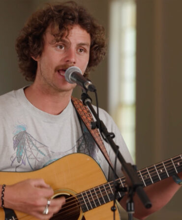 A man singing at a microphone and playing a guitar