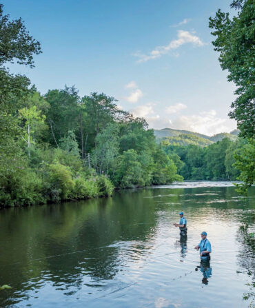 People fly fish in a river