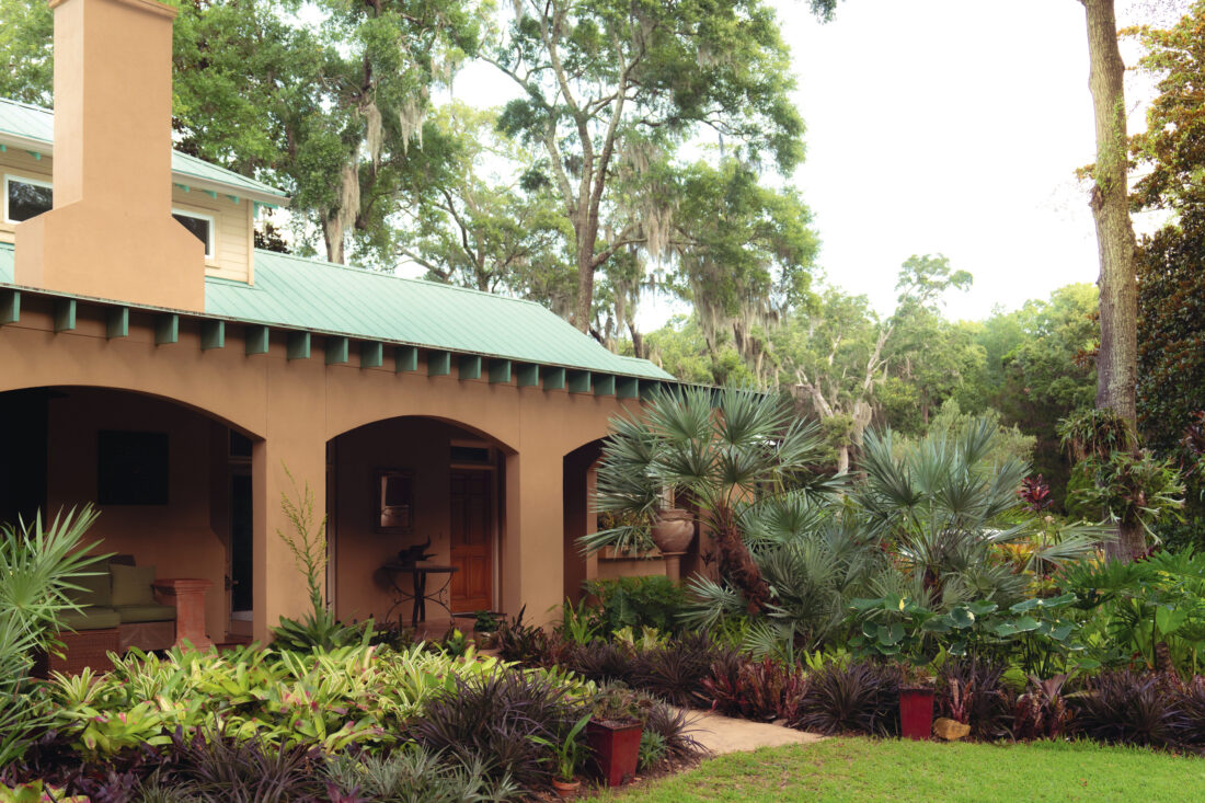 Tropical foliage surrounds a pueblo-style home.