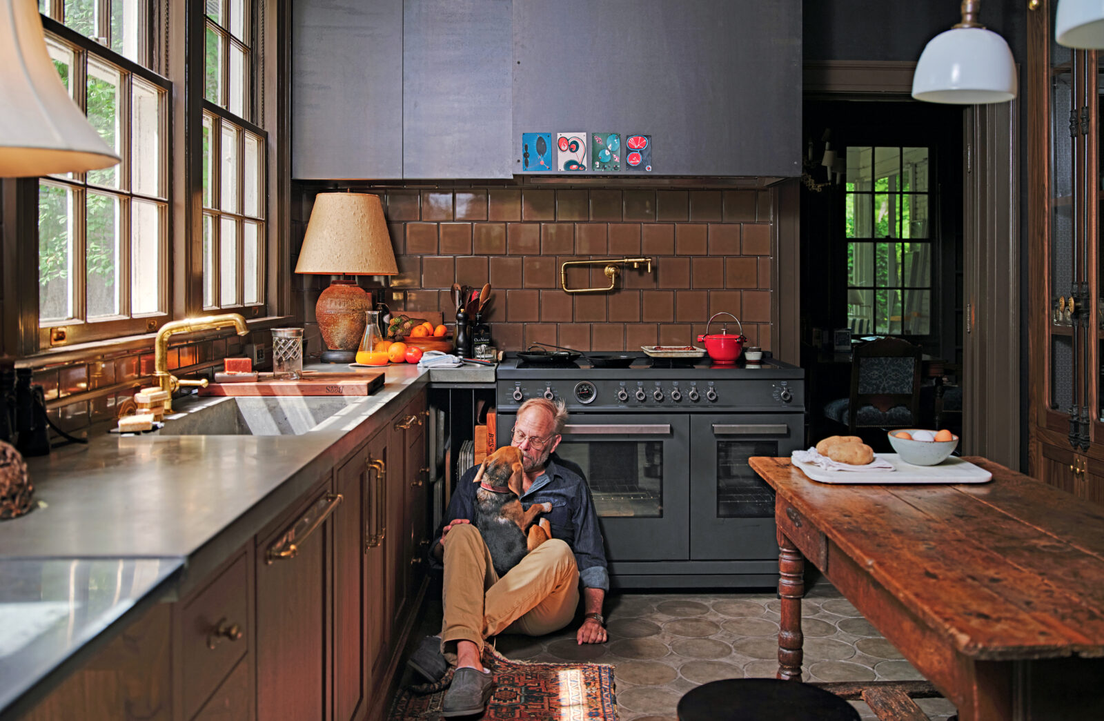 A man sits on a kitchen floor with a beagle in his lap