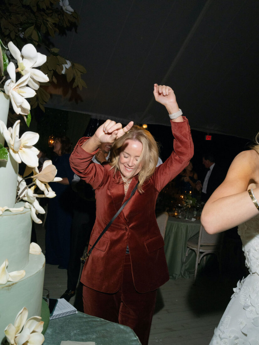 A woman in a red velvet suit dances by a cake
