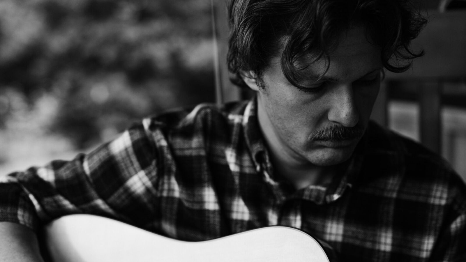 A close-up of a man with a guitar, shot in black and white