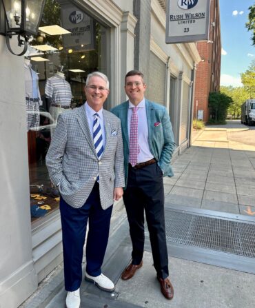 Two men smile outside of a store