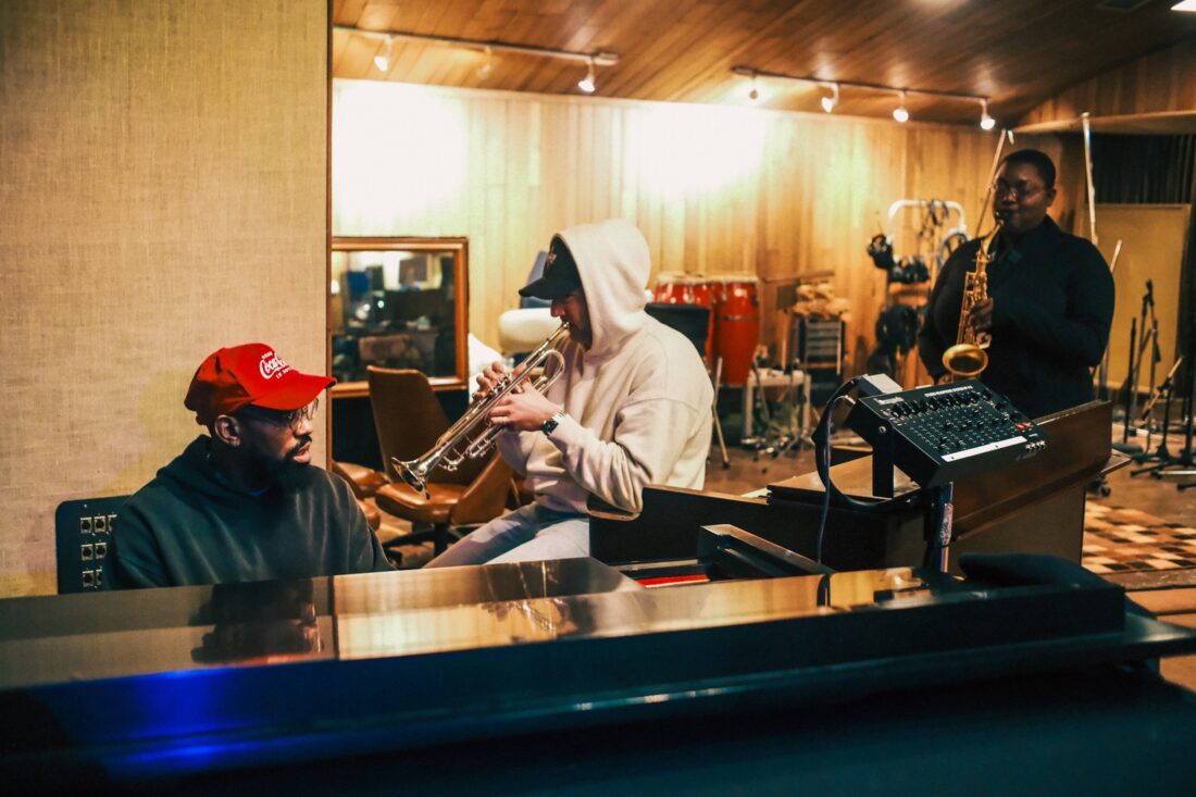 A group of three men work in a music studio