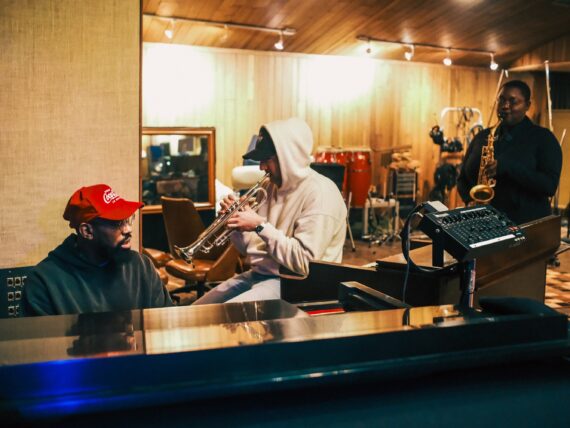 A group of three men work in a music studio
